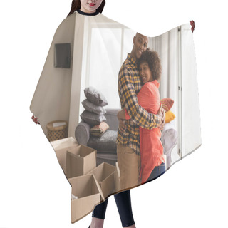 Personality  Portrait Of Happy Young Mixed-race Couple Embracing Each Other In Living Room At Home. They Are Surrounded By Cardboard Boxes. Hair Cutting Cape