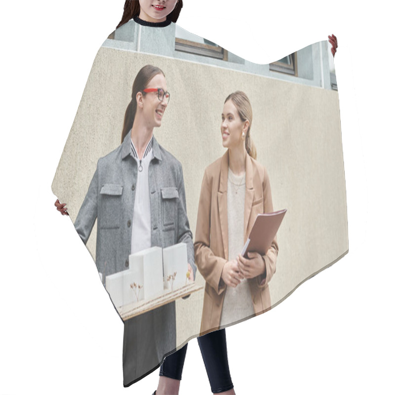 Personality  two smiling colleagues standing outdoors with scale model of building and paperwork, design bureau hair cutting cape