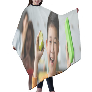 Personality  Cheerful Asian Boy Holding Lunch Box And Apple Near Blurred Kids In School Eatery, Banner Hair Cutting Cape