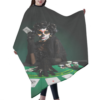 Personality  KYIV, UKRAINE - SEPTEMBER 12, 2022: Woman With Sugar Skull Makeup And Costume Holding Playing Card On Dark Green Hair Cutting Cape