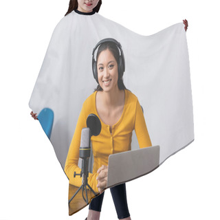 Personality  Joyful Asian Announcer In Wireless Headphones Looking At Camera While Sitting Near Laptop And Microphone Hair Cutting Cape