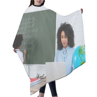 Personality  African American Teacher Using Laptop While Pupil Writing On Chalkboard On Blurred Background  Hair Cutting Cape