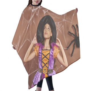 Personality  Girl In Halloween Costume And Witch Hat Looking Up And Standing Near Cobwebs On Brown Background Hair Cutting Cape