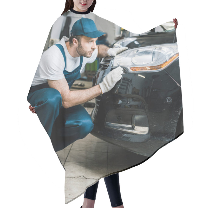 Personality  handsome bearded car mechanic looking at tail light in black car  hair cutting cape