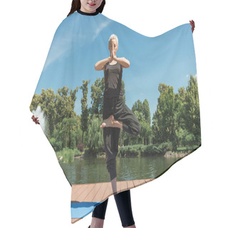 Personality  Woman Practicing Yoga In Tree Pose (Vrksasana) On Yoga Mat Near River In Park Hair Cutting Cape