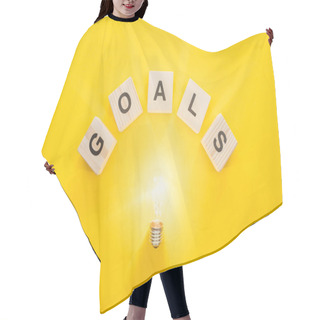Personality  Top View Of Glowing Light Bulb Under 'goals' Word Made Of Wooden Blocks On Yellow Background, Goal Setting Concept Hair Cutting Cape