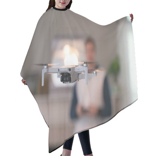Personality  Drone Flying Indoors With Pilot Visible In Background. Amateur Drone Flight. User Wearing Sweatshirt Flying Drone Inside Of Home On Cold Day. White Drone Flying Inside. Hair Cutting Cape