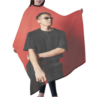 Personality  A Stylish And Handsome Asian Man Dressed In A Black Shirt And Black Pants Poses Against A Bold Red Background In A Studio. Hair Cutting Cape