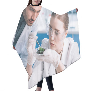 Personality  Biochemist In Goggles Holding Tweezers Near Green Plant And Coworker  Hair Cutting Cape