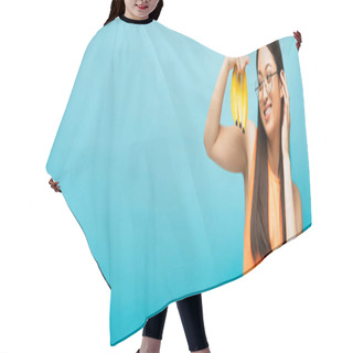 Personality  Horizontal Image Of Happy Asian Girl In Glasses Looking At Ripe Bananas Isolated On Blue  Hair Cutting Cape