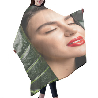 Personality  Close Up View Of Alluring Young Woman With Brunette Hair And Red Lips Smiling While Posing With Closed Eyes Around Tropical, Wet And Green Palm Leaves With Raindrops  Hair Cutting Cape