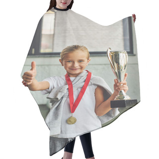 Personality  Vertical Shot Of Blonde Girl With Trophy And Golden Medal Showing Thumb Up At Camera, Child Sport Hair Cutting Cape