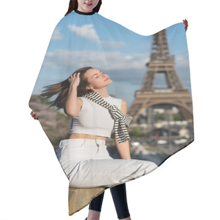 Personality  Young Stylish Woman With Closed Eyes Adjusting Hair And Sitting Near Eiffel Tower In Paris, France Hair Cutting Cape