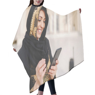 Personality  Portrait Of Charming Smiling Muslim Woman Dressed In Traditional Wear Using Smart Phone While Standing Outside. Hair Cutting Cape