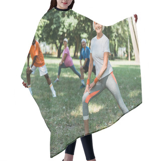 Personality  Selective Focus Of Cheerful Retired Woman Stretching Near Multicultural Pensioners On Grass  Hair Cutting Cape