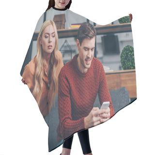 Personality  Jealous Young Woman Looking At Smiling Husband Using Smartphone On Couch, Distrust Concept Hair Cutting Cape