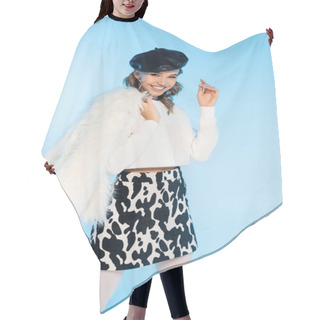 Personality  Cheerful Young Woman In Beret And Skirt With Cow Print Holding White Faux Fur Jacket While Posing On Blue Hair Cutting Cape