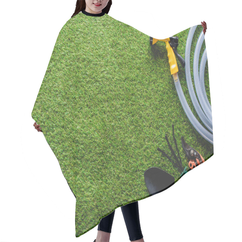 Personality  top view of hosepipe, hand rake, spade and secateurs on grass hair cutting cape