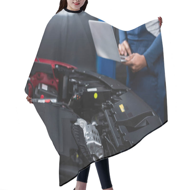 Personality  partial view of blurred african american mechanic with laptop near car engine compartment  hair cutting cape
