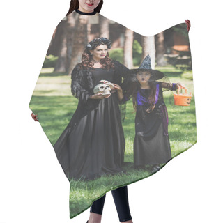 Personality  Woman In Vampire Halloween Costume Near Daughter In Witch Hat Grimacing While Holding Bucket With Candies Hair Cutting Cape