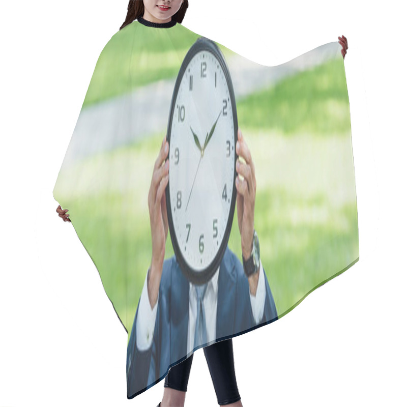 Personality  panoramic shot of businessman covering face with clock while standing in park hair cutting cape
