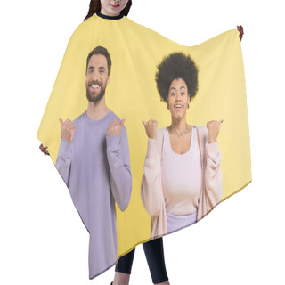 Personality  Cheerful Interracial Couple Pointing With Thumbs And Looking At Camera Isolated On Yellow Hair Cutting Cape