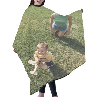 Personality  Top View Of Happy Young Mother Looking At Cheerful Toddler Son With Toy Biplane And Standing On Grass Hair Cutting Cape
