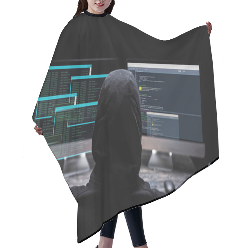 Personality  back view of hooded hacker sitting near computer monitors with data on screens on black  hair cutting cape