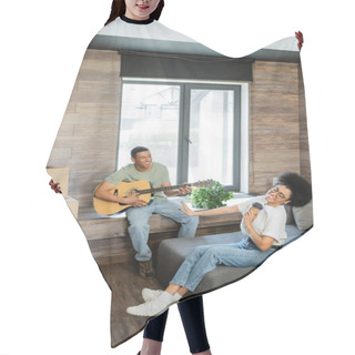 Personality  Happy African American Woman Holding Coffee Near Boyfriend Playing Acoustic Guitar In New House Hair Cutting Cape