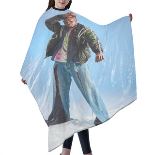 Personality  Good Looking Young Afroamerican Model In Outwear Jacket With Led Stripes And Ripped Jeans Touching Forehead And Standing On Glossy Cellophane On Blue Background, Urban Outfit And DIY Clothing  Hair Cutting Cape