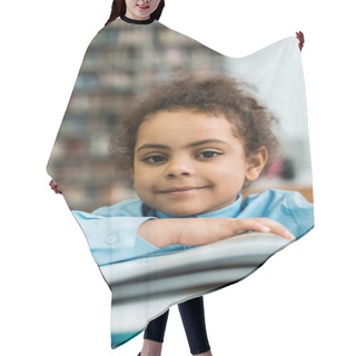 Personality  Selective Focus Of Happy African American Kid Looking At Camera Near Book On Table  Hair Cutting Cape