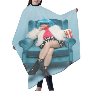 Personality  Asian Woman In Pop Arty Style Holding Popcorn While Sitting On Velveteen Armchair On Blue Background  Hair Cutting Cape