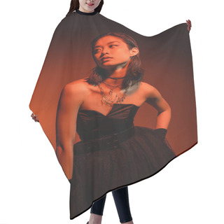 Personality  Asian Woman With Short Hair And Wet Hairstyle Posing With Hand On Hip In Black Strapless Dress With Tulle Skirt And Gloves While Standing On Orange Background With Red Lighting, Golden Jewelry  Hair Cutting Cape