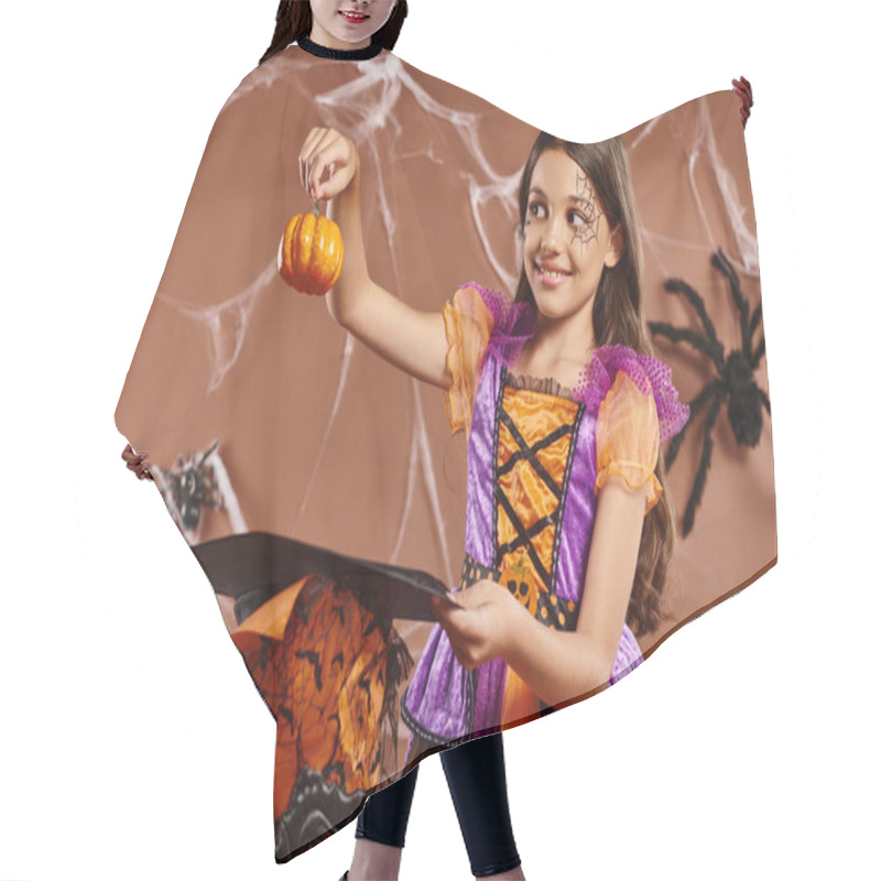 Personality  Positive Child In Halloween Witch Costume Holding Pumpkin Near Pointed Hat On Brown Background Hair Cutting Cape