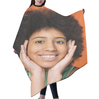 Personality  Portrait Of Positive And Stylish African American Teenager With Bold Makeup Touching Face And Looking At Camera While Posing Isolated On Orange, Trendy Teenage Girl Expressing Individuality  Hair Cutting Cape