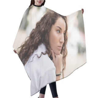 Personality  Portrait Of Young Curly And Pensive Woman In White T-shirt Looking Away And Holding Hand Near Chin While Standing On Blurred Urban Street In Barcelona, Spain  Hair Cutting Cape
