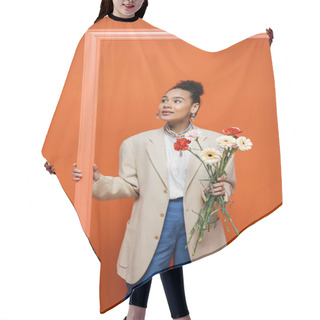 Personality  Smiling Fashion Model In Trendy Attire With Accessories Holding Orange Framework And Flower Bouquet Hair Cutting Cape