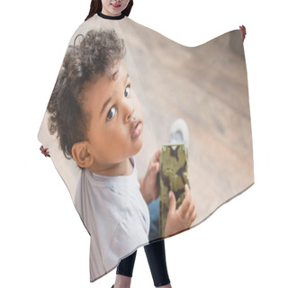Personality  Overhead View Of Curly African American Child Looking At Camera While Holding Toy Hair Cutting Cape