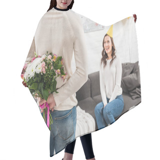Personality  Back View Of Man Holding Birthday Flowers Behind Back With Woman Sitting On Couch  Hair Cutting Cape