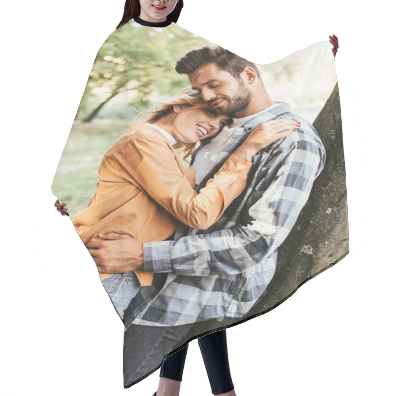 Personality  Attractive Young Woman Embracing Boyfriend While Standing Near Tree Trunk In Park Hair Cutting Cape