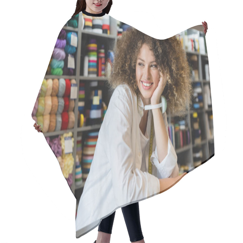 Personality  Happy Saleswoman With Needle Cushion On Hand Looking Away Near Counter And Rack With Needlework Accessories Hair Cutting Cape