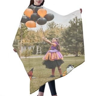 Personality  Joyful Girl In Halloween Costume Holding Balloons Near Pumpkin, Witch Hat And Candy Bucket On Grass Hair Cutting Cape