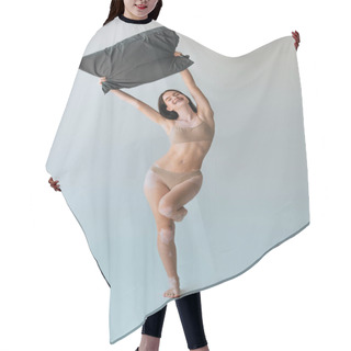 Personality  Full Length Of Smiling Woman With Braces And Vitiligo Skin Condition Holding Pillow Above Head On Grey  Hair Cutting Cape