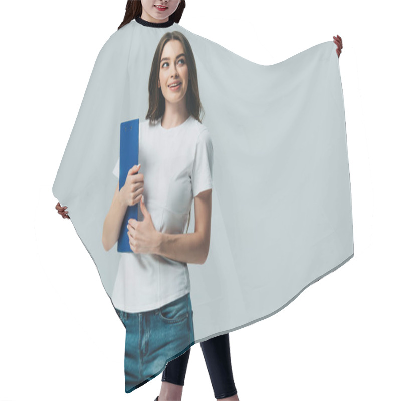 Personality  happy beautiful girl in white t-shirt holding clipboard looking away isolated on grey hair cutting cape