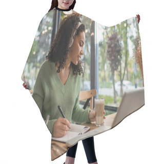 Personality  African American Woman Listening Podcast In Headphones And Holding Glass With Coffee Near Laptop In Cafe  Hair Cutting Cape