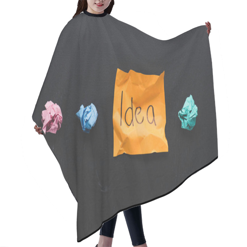 Personality  top view of 'idea' word written on sticky note with colorful crumpled paper balls on black background, ideas concept hair cutting cape