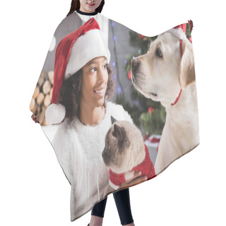 Personality  Smiling African American Girl In Santa Hat Looking At Labrador Dog While Holding Fluffy Cat   On Blurred Background Hair Cutting Cape