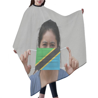 Personality  A Woman With Tanzania Flag On Hygienic Mask In Her Hand And Lifted Up The Front Face On Beige Color Background. Tiny Particle Or Virus Corona Or Covid 19 Protection. Concept Of Combating Illness. Hair Cutting Cape
