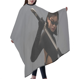 Personality  Brunette Asian Woman In Black Clothes And Sunglasses Pulling Out Katana From Scabbard Isolated On Grey Hair Cutting Cape