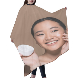 Personality  Positive Asian Woman With Naked Shoulders Applying Face Cream Isolated On Brown  Hair Cutting Cape